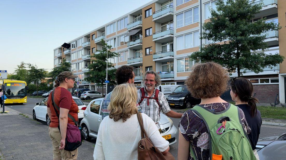 Deelnemers van de buurtsafari in Kanaleneiland staan bij elkaar en luisteren naar hovenier Rob van der Steen